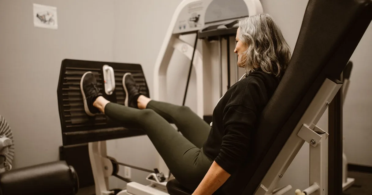 Mulher madura fazendo leg press em um aparelho de academia com carga leve